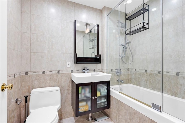 full bath featuring tiled shower / bath, toilet, vanity, and tile walls