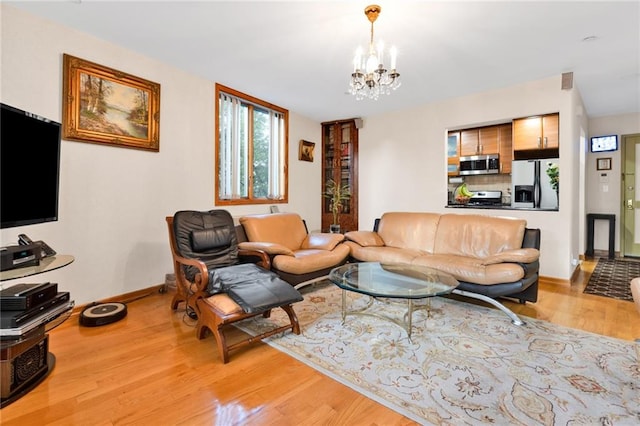 living room featuring light wood-type flooring, a notable chandelier, and baseboards