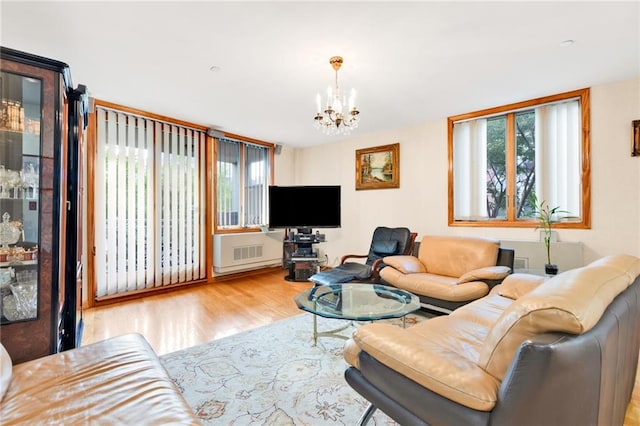 living room featuring an inviting chandelier, radiator heating unit, a wealth of natural light, and wood finished floors