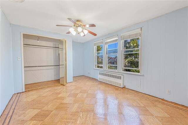 unfurnished bedroom with ceiling fan, light parquet flooring, radiator heating unit, and a closet