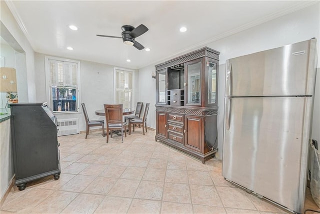 kitchen with light tile patterned floors, ornamental molding, stainless steel fridge, radiator, and ceiling fan