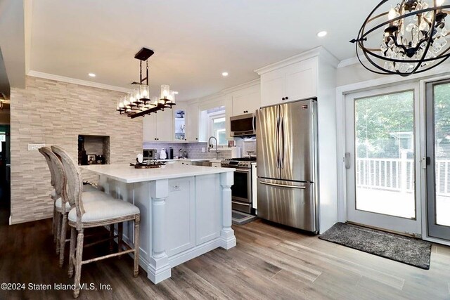 kitchen with a notable chandelier, decorative backsplash, white cabinetry, hanging light fixtures, and appliances with stainless steel finishes