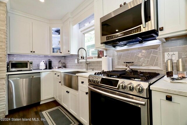 kitchen with light stone countertops, white cabinets, appliances with stainless steel finishes, tasteful backsplash, and sink