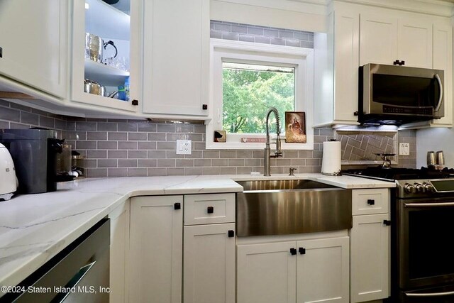 kitchen with stainless steel appliances, backsplash, white cabinetry, and sink