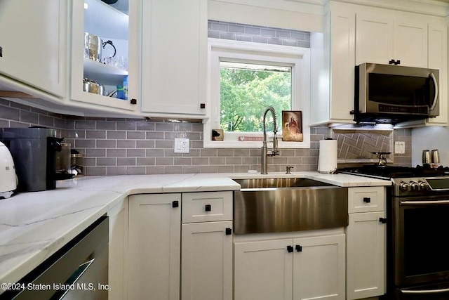 kitchen featuring white cabinets, tasteful backsplash, stainless steel appliances, and a sink