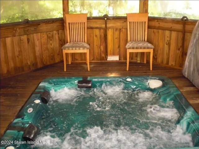 unfurnished room with hardwood / wood-style floors, wood walls, and a jacuzzi