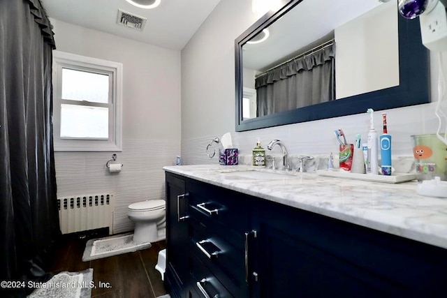 bathroom with toilet, tile walls, visible vents, radiator heating unit, and vanity