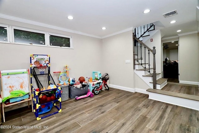 recreation room featuring wood finished floors, baseboards, ornamental molding, visible vents, and recessed lighting