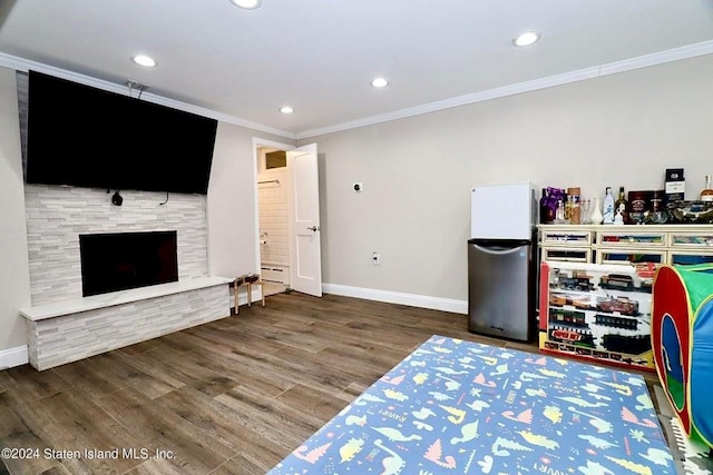 bedroom with baseboard heating, a fireplace, refrigerator, hardwood / wood-style flooring, and crown molding