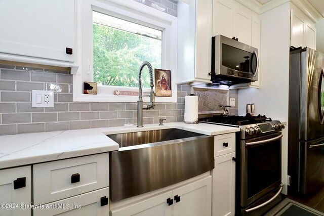 kitchen featuring stainless steel appliances, backsplash, and white cabinets