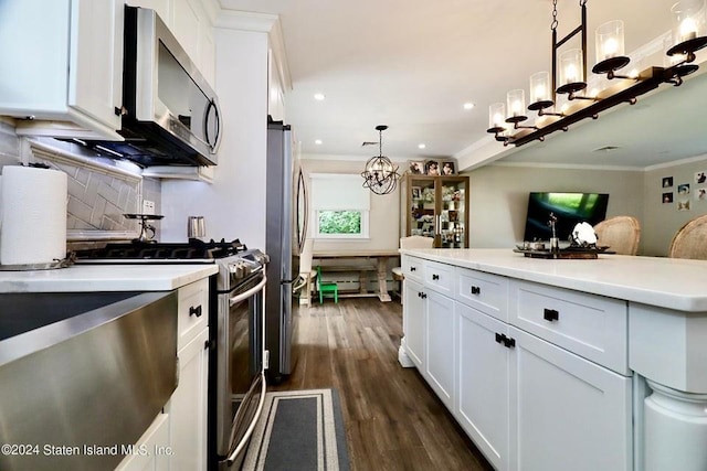 kitchen featuring crown molding, a chandelier, white cabinetry, backsplash, and appliances with stainless steel finishes