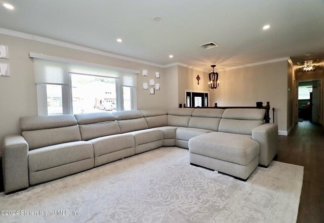 living room featuring a notable chandelier, ornamental molding, and light hardwood / wood-style flooring