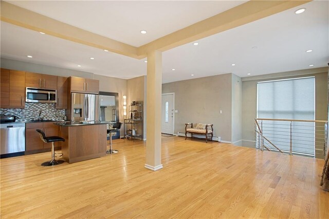 kitchen with appliances with stainless steel finishes, a center island, a breakfast bar area, and light hardwood / wood-style flooring