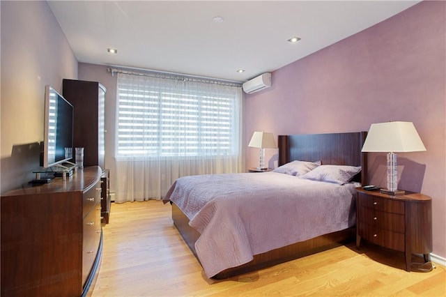 bedroom featuring light hardwood / wood-style floors and a wall unit AC