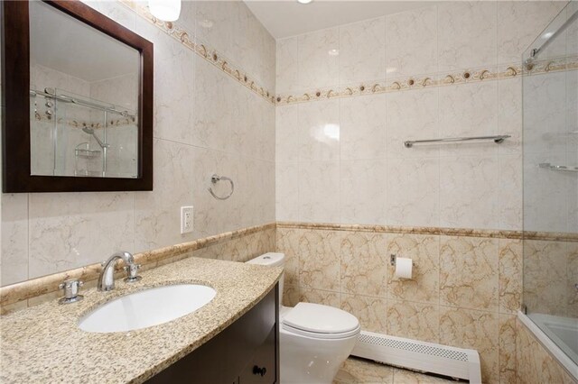 full bathroom with a baseboard radiator, bathtub / shower combination, tile walls, vanity, and toilet