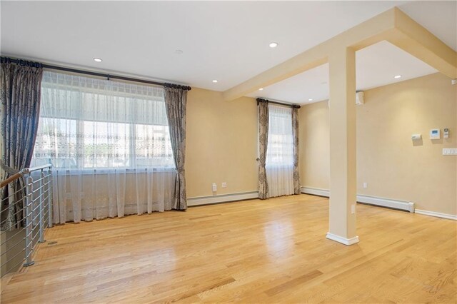 unfurnished room with beamed ceiling, a baseboard radiator, and light wood-type flooring