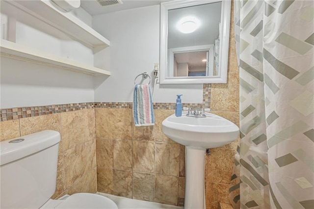 bathroom with a shower with shower curtain, tile walls, and toilet