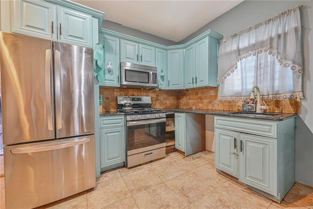 kitchen featuring decorative backsplash, appliances with stainless steel finishes, dark stone counters, sink, and light tile patterned flooring