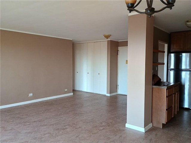 kitchen featuring baseboards, ornamental molding, and freestanding refrigerator