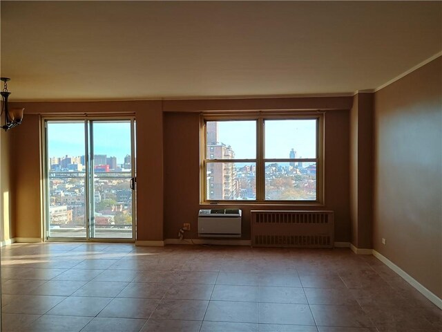 spare room featuring crown molding, plenty of natural light, radiator heating unit, and light tile patterned floors