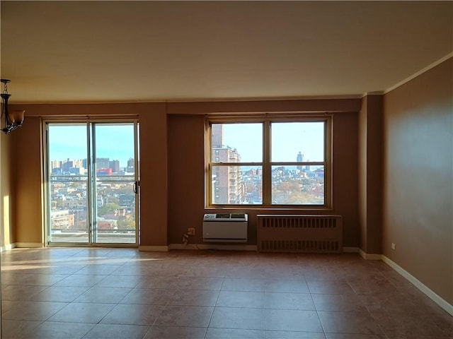 empty room featuring radiator heating unit, ornamental molding, a chandelier, tile patterned flooring, and baseboards