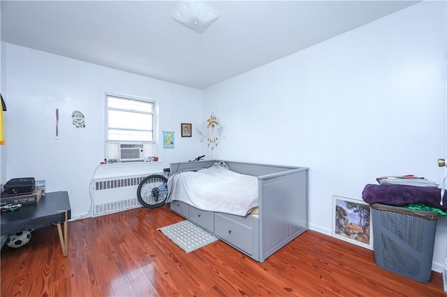 bedroom featuring cooling unit, dark hardwood / wood-style flooring, and radiator heating unit