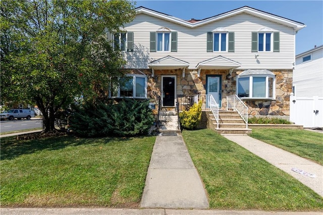 townhome / multi-family property featuring stone siding and a front lawn