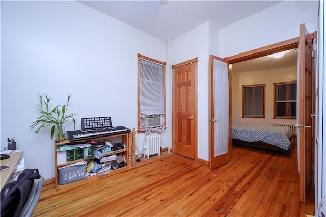 interior space with cooling unit, wood-type flooring, and radiator heating unit