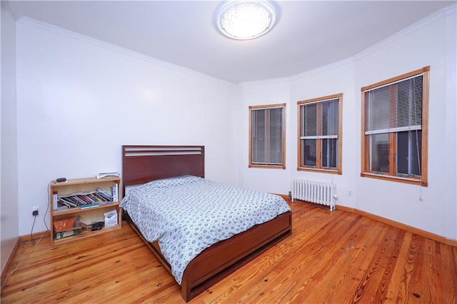 bedroom with crown molding, radiator heating unit, and hardwood / wood-style floors