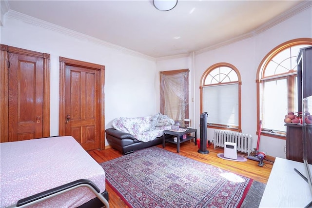 bedroom featuring crown molding, wood-type flooring, and radiator heating unit