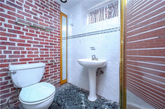 bathroom featuring toilet, sink, and brick wall