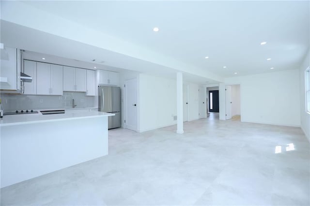 kitchen with white cabinetry, black electric stovetop, stainless steel fridge, and tasteful backsplash