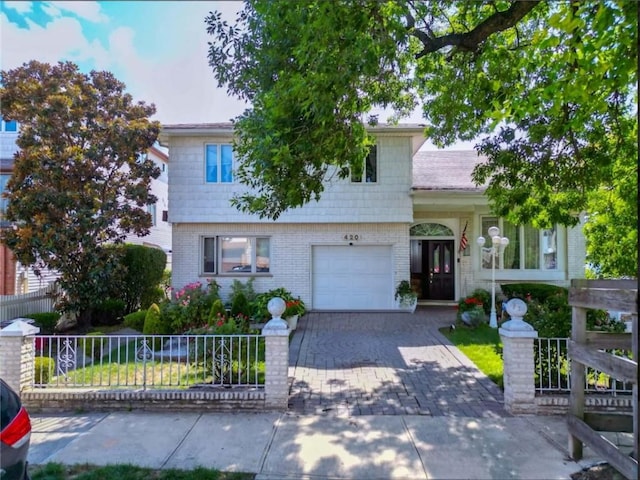 tri-level home with an attached garage, fence, decorative driveway, and brick siding