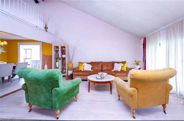 living room with vaulted ceiling, light hardwood / wood-style floors, and a chandelier