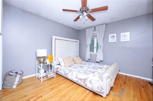 bedroom with a ceiling fan, baseboards, and wood finished floors