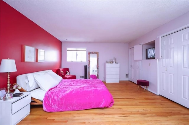 bedroom with light wood-type flooring and multiple closets