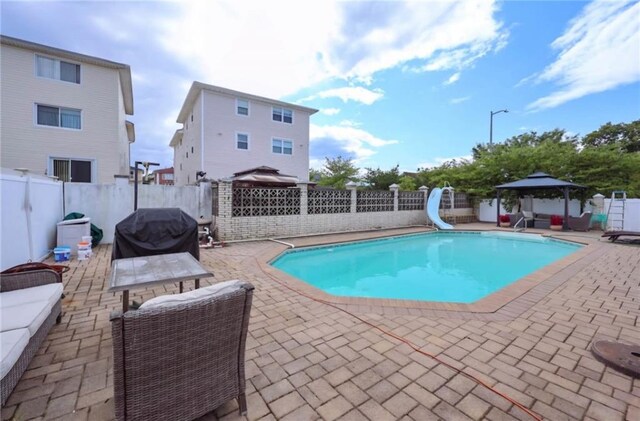 view of swimming pool featuring a gazebo, area for grilling, a water slide, and a patio