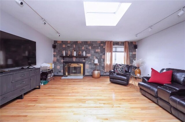 living room featuring a skylight, track lighting, and light wood-type flooring