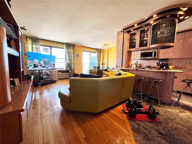 living room with a chandelier, light wood-type flooring, and sink