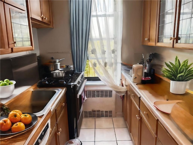 kitchen with radiator heating unit, gas stove, and light tile patterned flooring