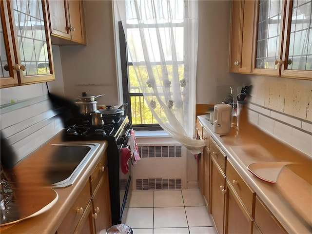 kitchen with range, decorative backsplash, radiator heating unit, and light tile patterned flooring