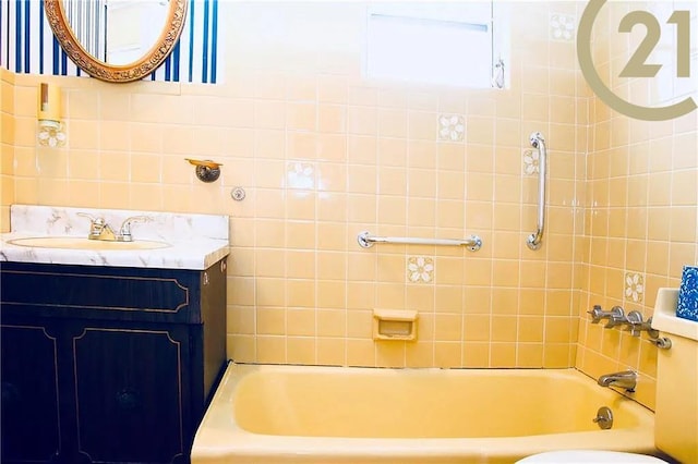 full bathroom featuring tiled shower / bath, vanity, tile walls, and toilet