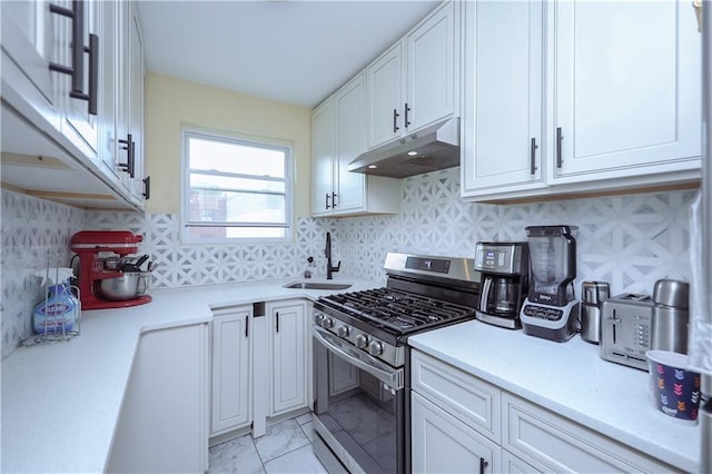 kitchen with light countertops, gas stove, a sink, and under cabinet range hood