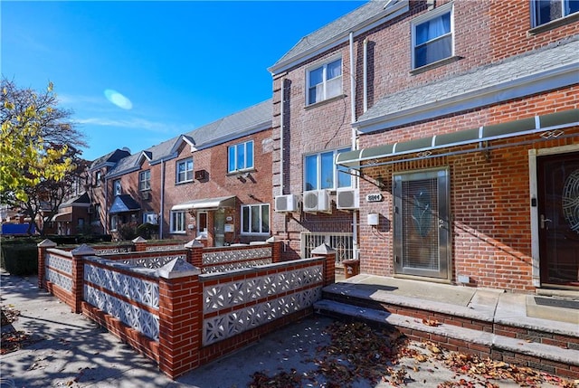 exterior space featuring brick siding, cooling unit, and a residential view