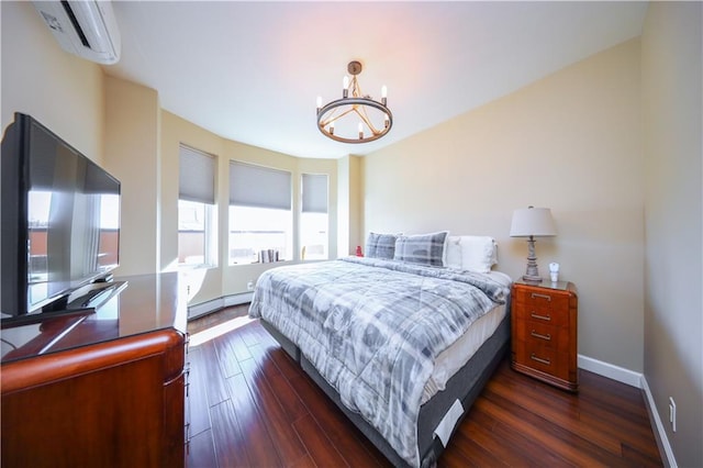 bedroom featuring a baseboard heating unit, dark wood-style flooring, a wall unit AC, and baseboards