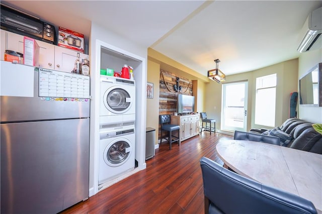 washroom with a wall unit AC, stacked washer and dryer, laundry area, and dark wood-type flooring