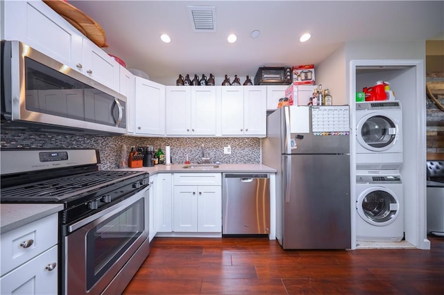 kitchen featuring appliances with stainless steel finishes, white cabinetry, visible vents, and stacked washer / drying machine