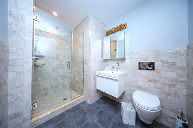 full bath with a stall shower, toilet, tile patterned floors, vanity, and tile walls