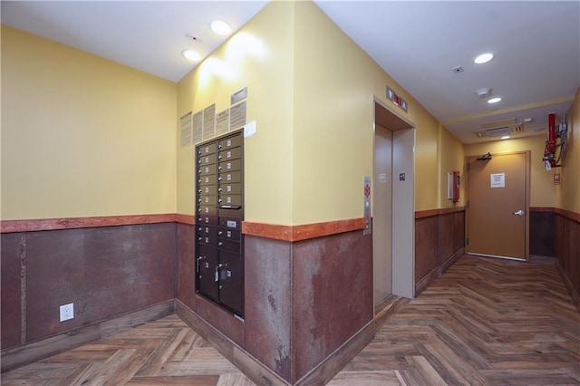 corridor with dark parquet flooring, mail boxes, and elevator