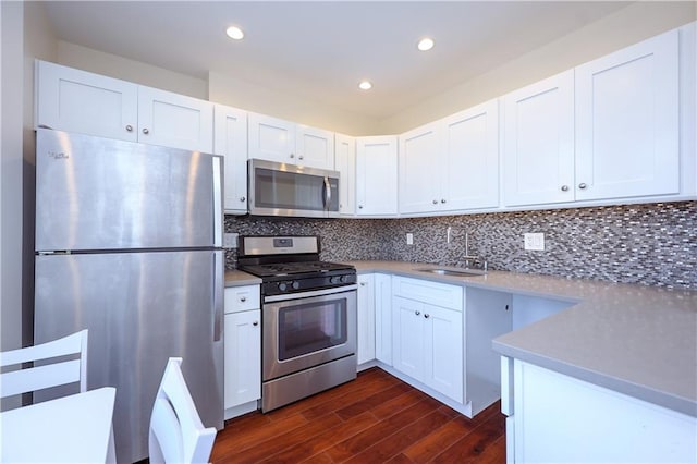 kitchen with white cabinetry, sink, dark wood-type flooring, stainless steel appliances, and tasteful backsplash